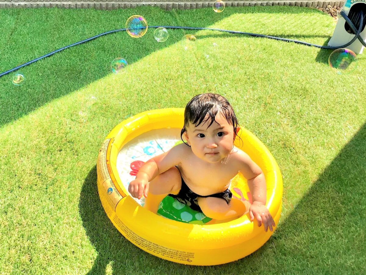 庭でプール遊びをする赤ちゃん